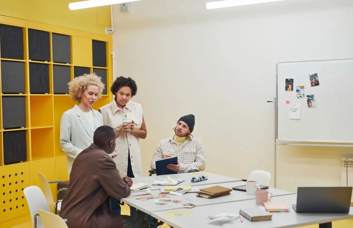 Equipo de trabajo en una reunión en sala de juntas revisando un plan con computadores y documentos