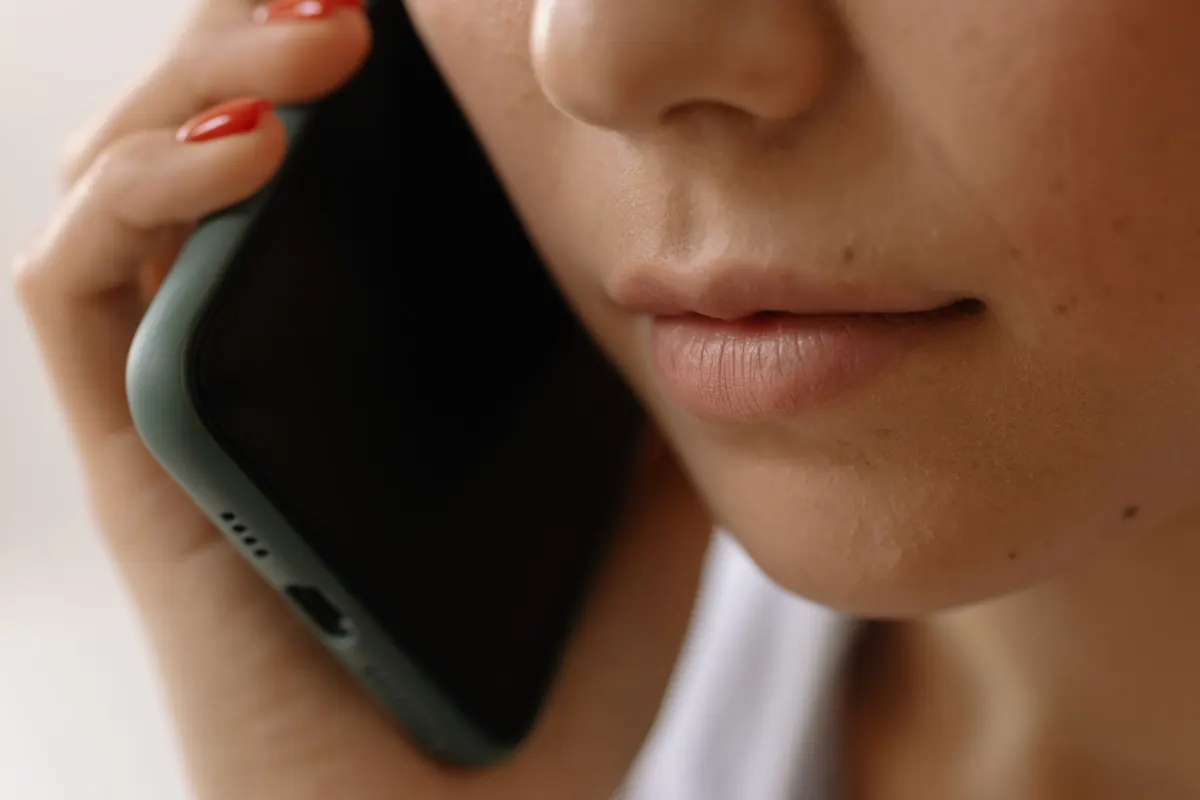 Primer plano de una mujer que habla por celular para pedir una cita