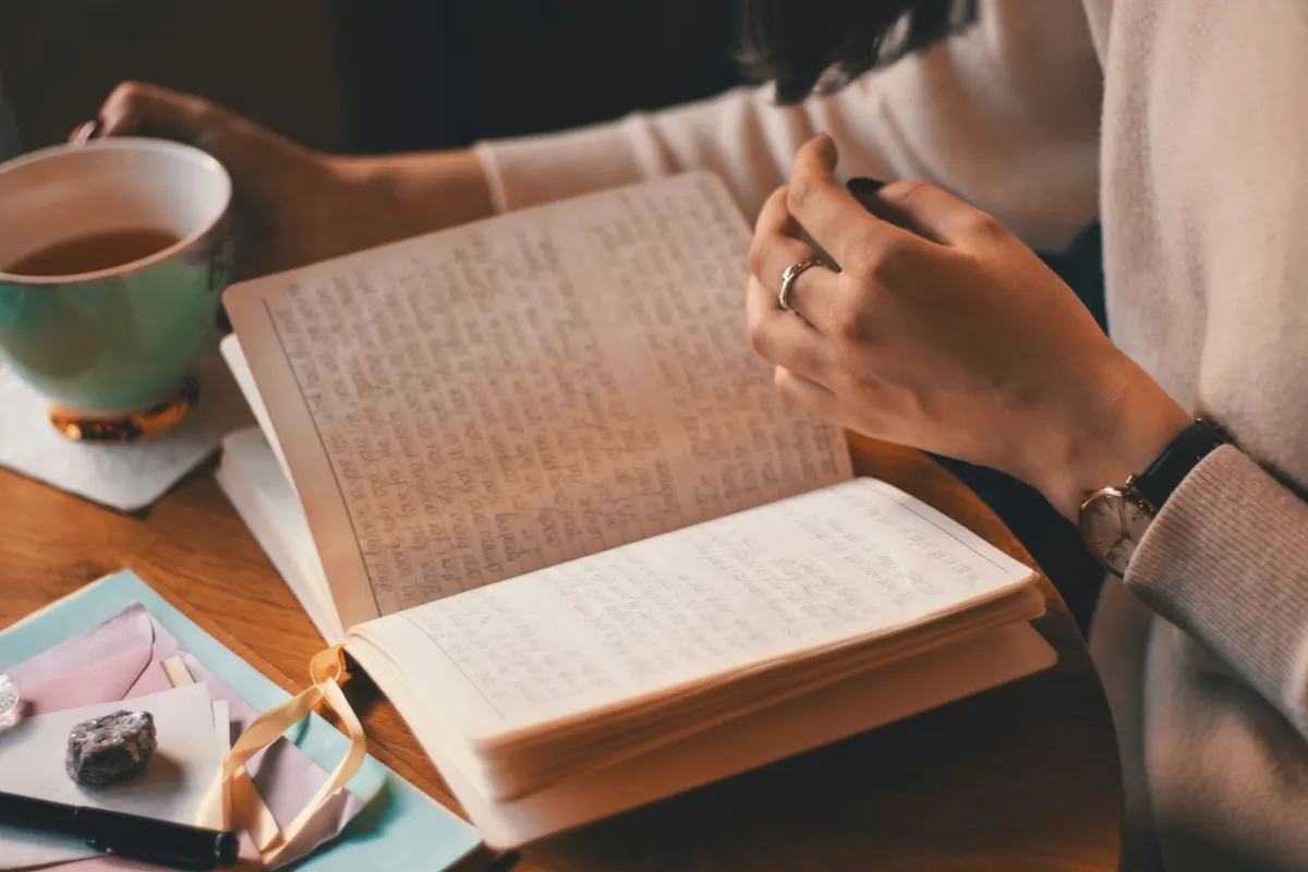 Persona escribe en un cuaderno junto a una taza de café, anotando ideas antes de su cita
