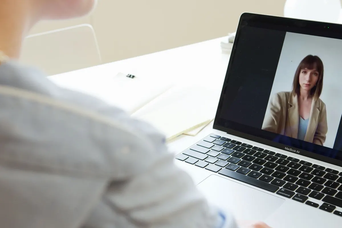 Pantalla de un portátil con una videollamada con una profesional, vista sobre el hombro de quien consulta